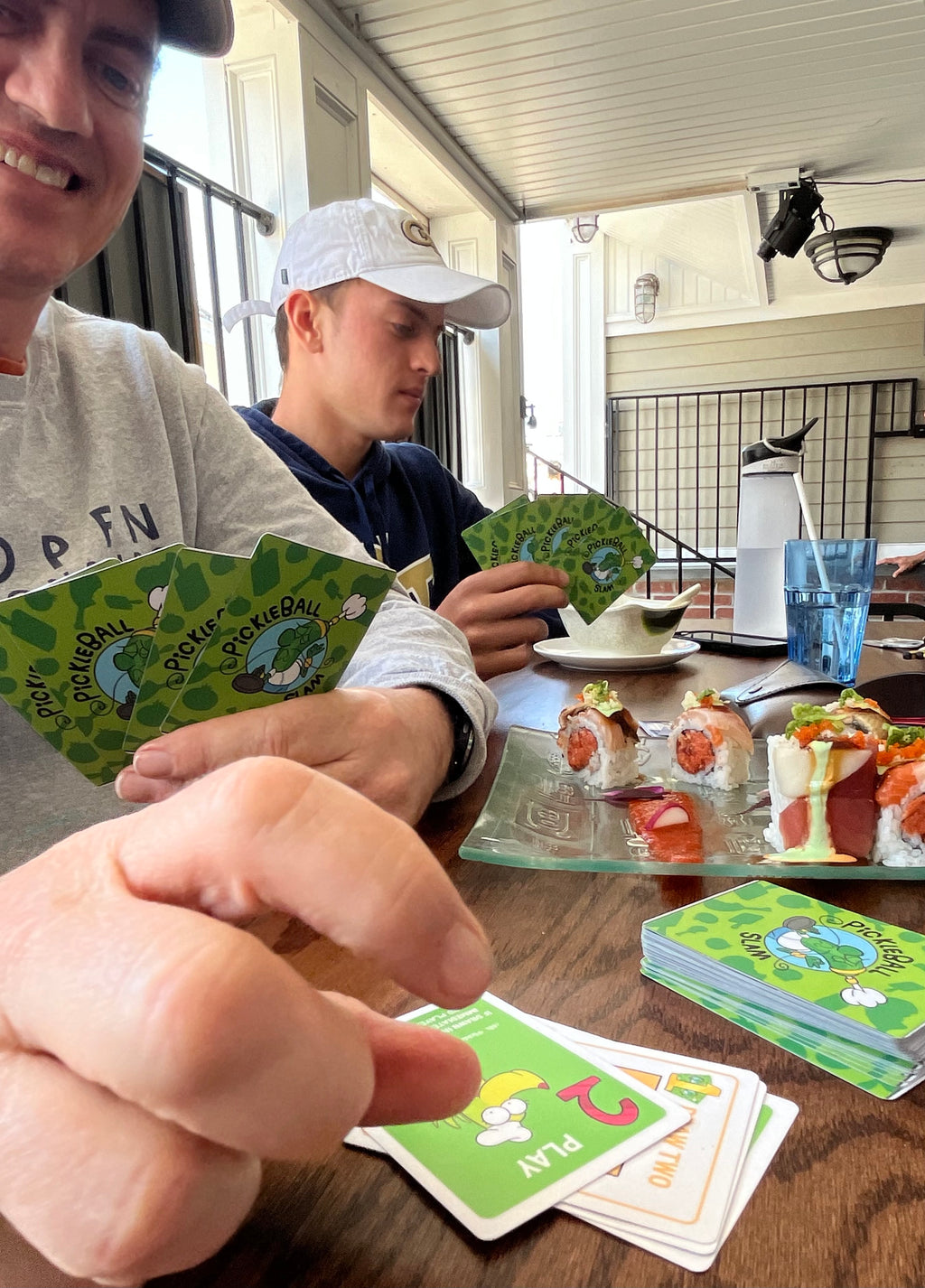 Dad and son playing card game while eating sushi