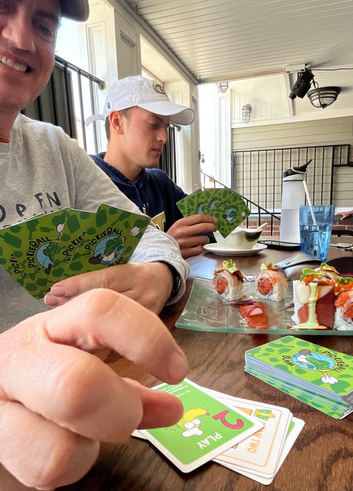 Dad and son playing card game while eating sushi